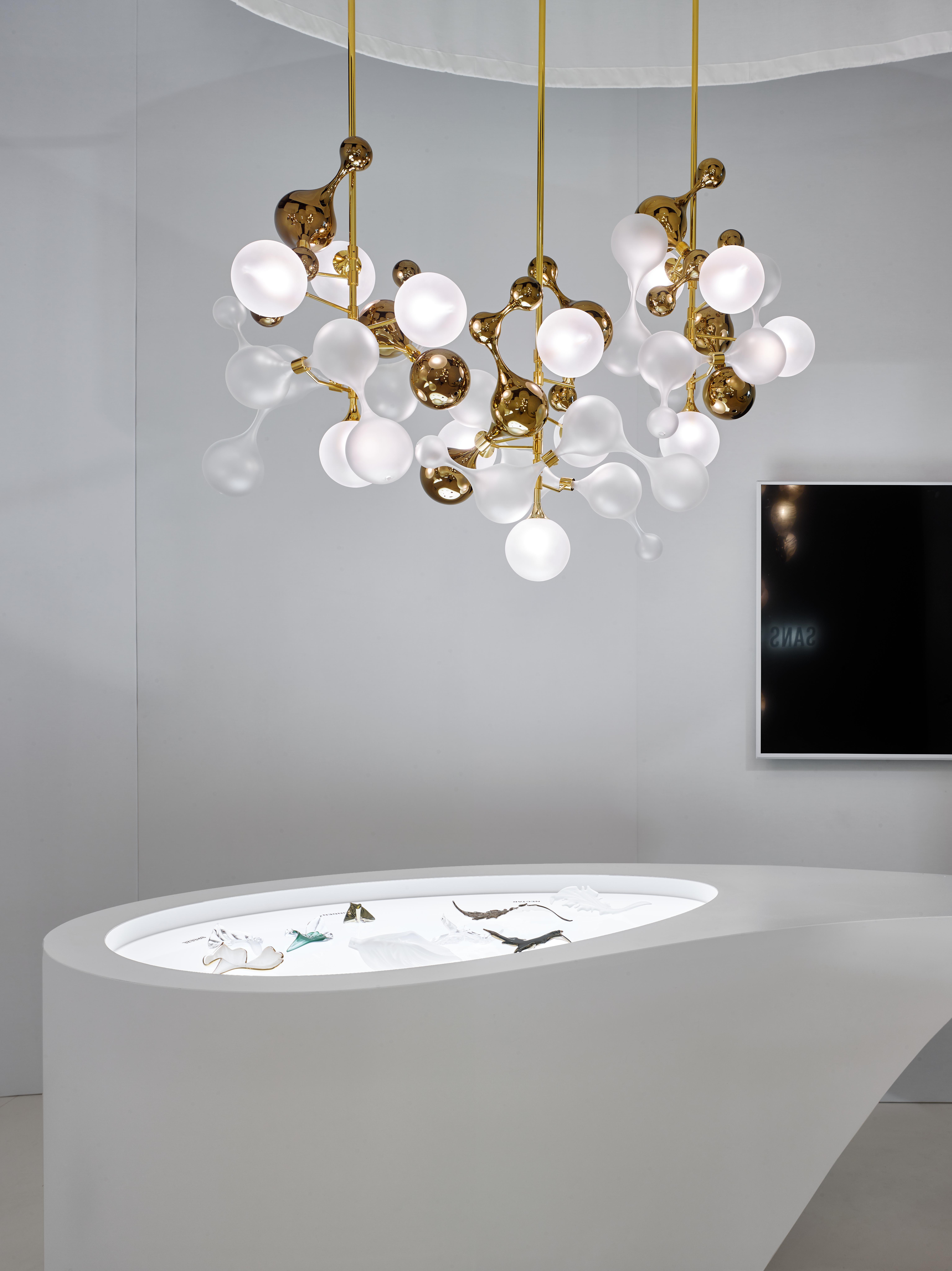 The PARTICLES collection features magnificent chandeliers formed of interconnecting complex glass shapes inspired by the microscopic design of powerful joy hormones – serotonin, dopamine and adrenaline. The glass components are finished in crystal, sandblasted and aurum nanocoating and fitted around a polished brass stem, to create bold artistic centrepiece for your space.